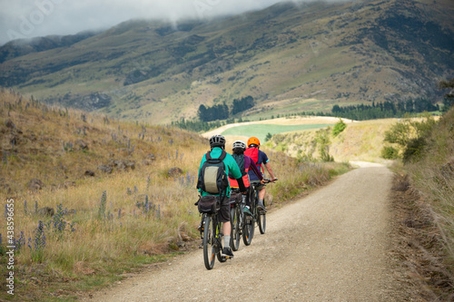 Fototapeta Naklejka Na Ścianę i Meble -  Three people cycling the Otago Central Rail Trail in a row towards Middlemarch, South Island, New Zealand