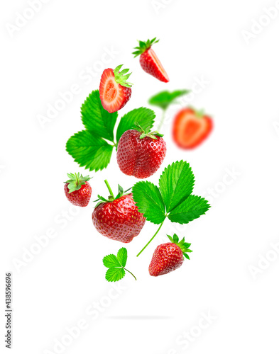 Fototapeta Naklejka Na Ścianę i Meble -  Ripe fresh flying red strawberry, green leaves isolated on white background. Strawberry pattern Summer delicious sweet berry organic fruit food diet vitamins creative layout. Whole and halved berries