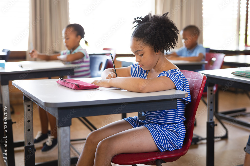 African american girl studying while sitting on her desk in the class at school African american girl studying while sitting on her desk in the class at school