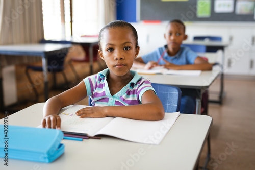Portrait of african american girl sitting on her desk in the class at school