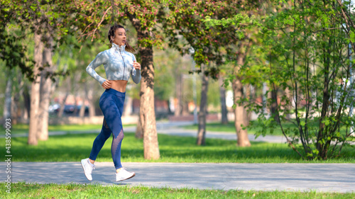 Full length photo of a woman running in park in early morning. Attractive looking woman keeping fit and healthy. Format 16x9.
