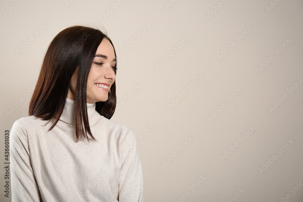 Portrait of pretty young woman with gorgeous chestnut hair and charming smile on light background, space for text Portrait of pretty young woman with gorgeous chestnut hair and charming smile on light background, space for text