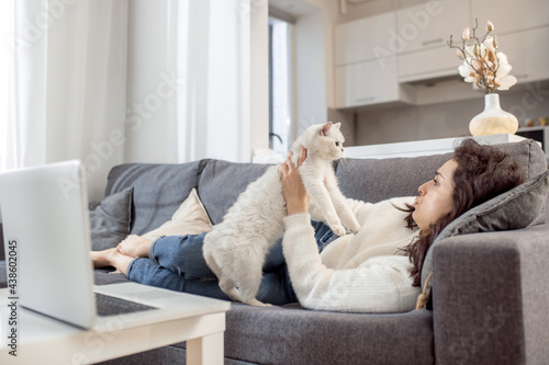 Young woman laying on the sofa with her cat and looking relaxed