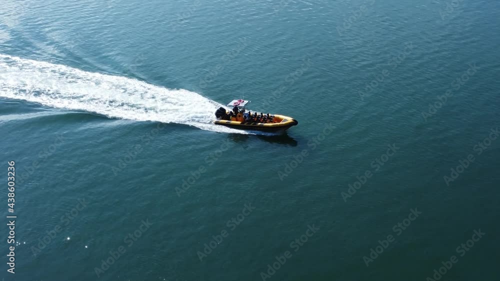 Sightseeing motor boat speeding across turquoise shimmering ocean surface leaving foaming wake aerial tracking right view Sightseeing motor boat speeding across turquoise shimmering ocean surface leaving foaming wake aerial tracking right view