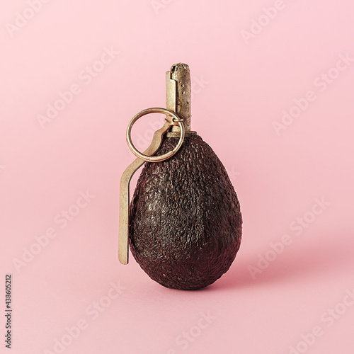 The creative concept of the diet. Avocado in the shape of a grenade on a pink background. photo