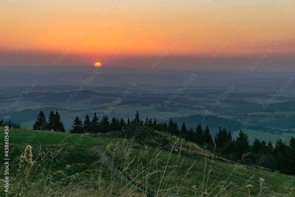 Sunset from Wasserkuppe, the highest point in Roehn Mountains with meadow in foreground under a clear sky, Germany