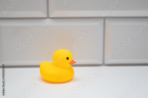 Yellow bath toy duck on a white brick wall in the bathroom