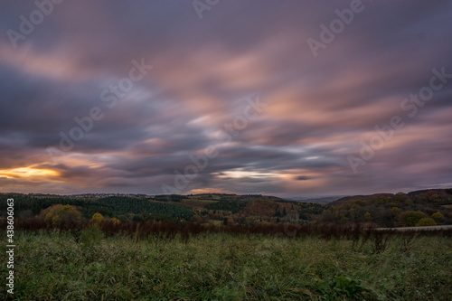 long exposure of german landscape of Hunsrueck in autumn with thick colorful clouds at sunset in the evening