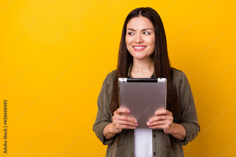 Photo of attractive nice pretty mature woman look empty space hold hands tablet isolated on yellow color background Photo of attractive nice pretty mature woman look empty space hold hands tablet isolated on yellow color background