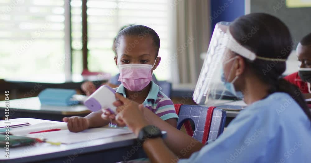 Diverse medical worker showing schoolgirl how to measure temperature, all wearing face masks, Diverse medical worker showing schoolgirl how to measure temperature, all wearing face masks,