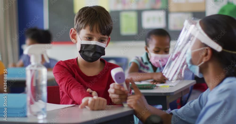 Diverse medical worker showing schoolboy how to measure temperature, all wearing face masks, Diverse medical worker showing schoolboy how to measure temperature, all wearing face masks,