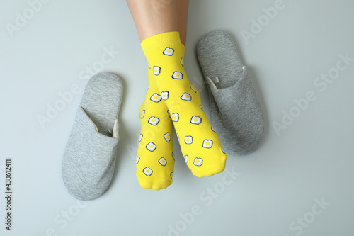 Female legs in funny socks on gray background with slippers photo