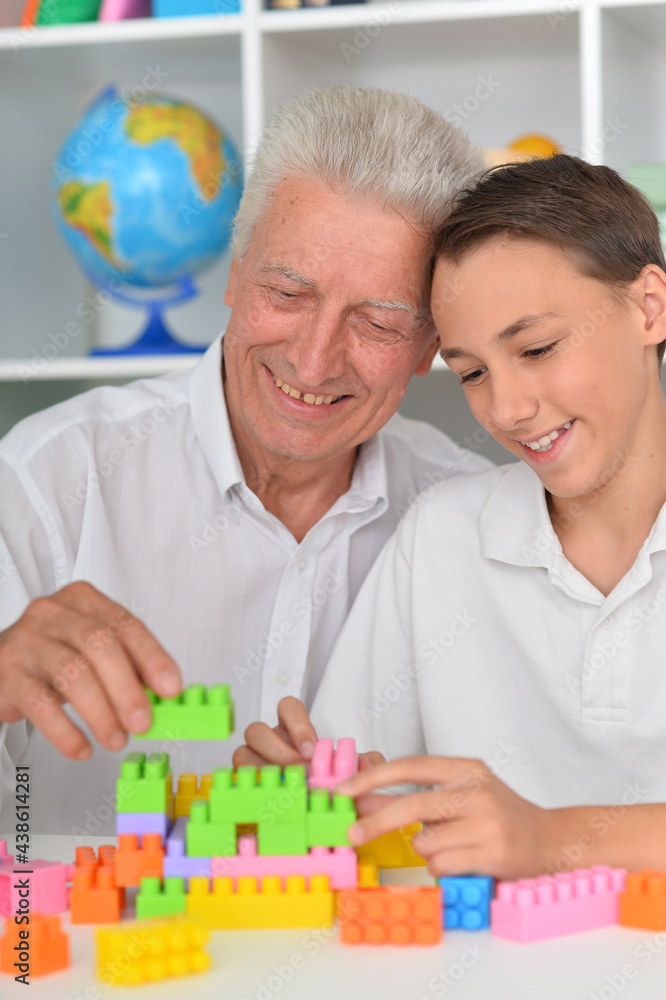 Smiling boy playing with colorful plastic blocks with grandfather Smiling boy playing with colorful plastic blocks with grandfather