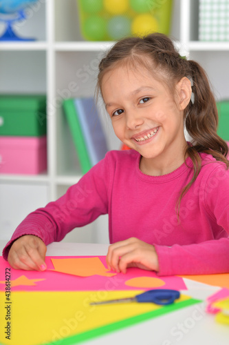 Porait of cute little girl is cutting paper