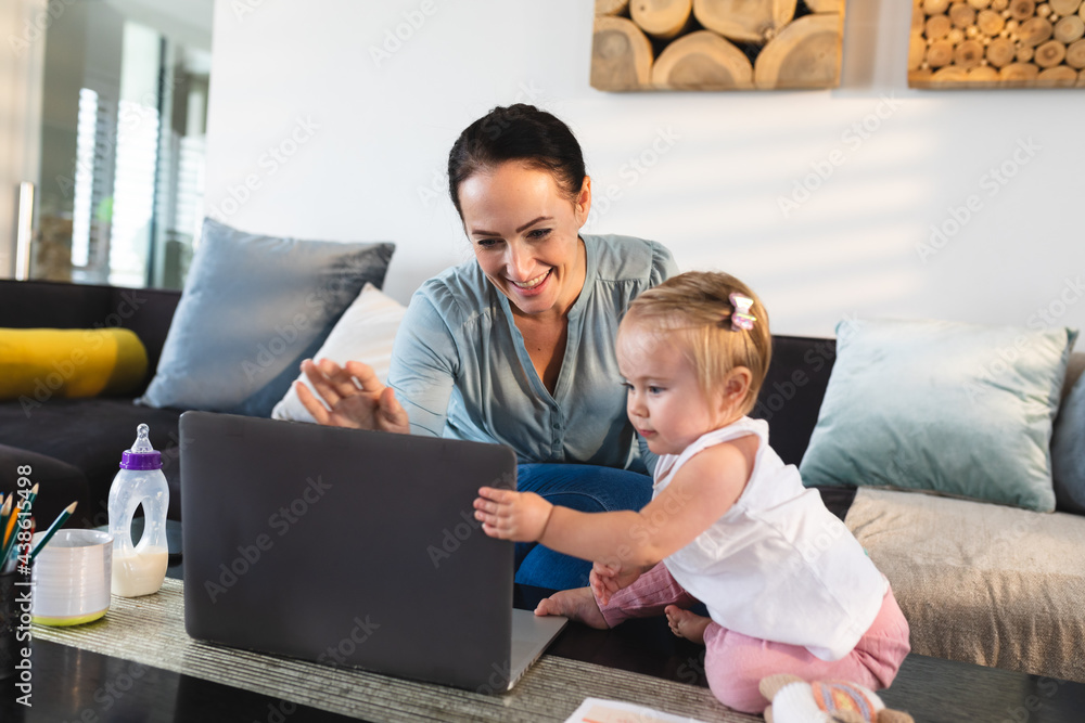 Smiling caucasian mother and her baby looking at laptop at home Smiling caucasian mother and her baby looking at laptop at home