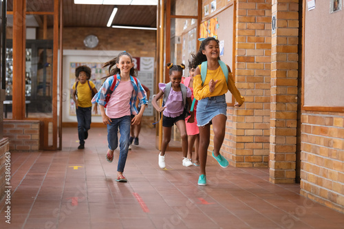 Group of diverse students running together in the corridor at school photo