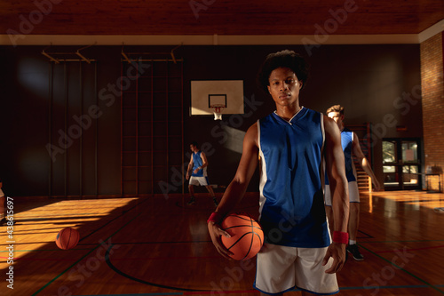 Portrait of mixed race male basketball player with team in background photo