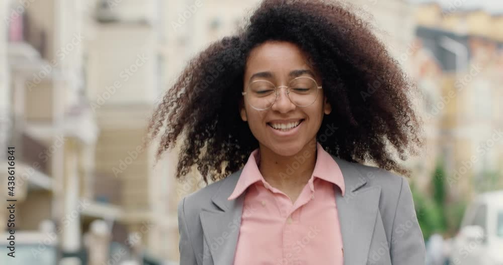 Portrait of Confident Smiling Afro American Woman in Eyeglasses Walking. Successful Mixed Race Female in Classic Clothes looking into Camera. Curly hair. Ethnic Girl. Feeling Independent. Portrait of Confident Smiling Afro American Woman in Eyeglasses Walking. Successful Mixed Race Female in Classic Clothes looking into Camera. Curly hair. Ethnic Girl. Feeling Independent.