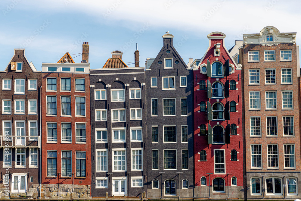 Architecture features traditional houses, Typical dutch house at Damrak canal,  An avenue running between Amsterdam Centraal in the north and Dam Square in the south, Netherlands.
