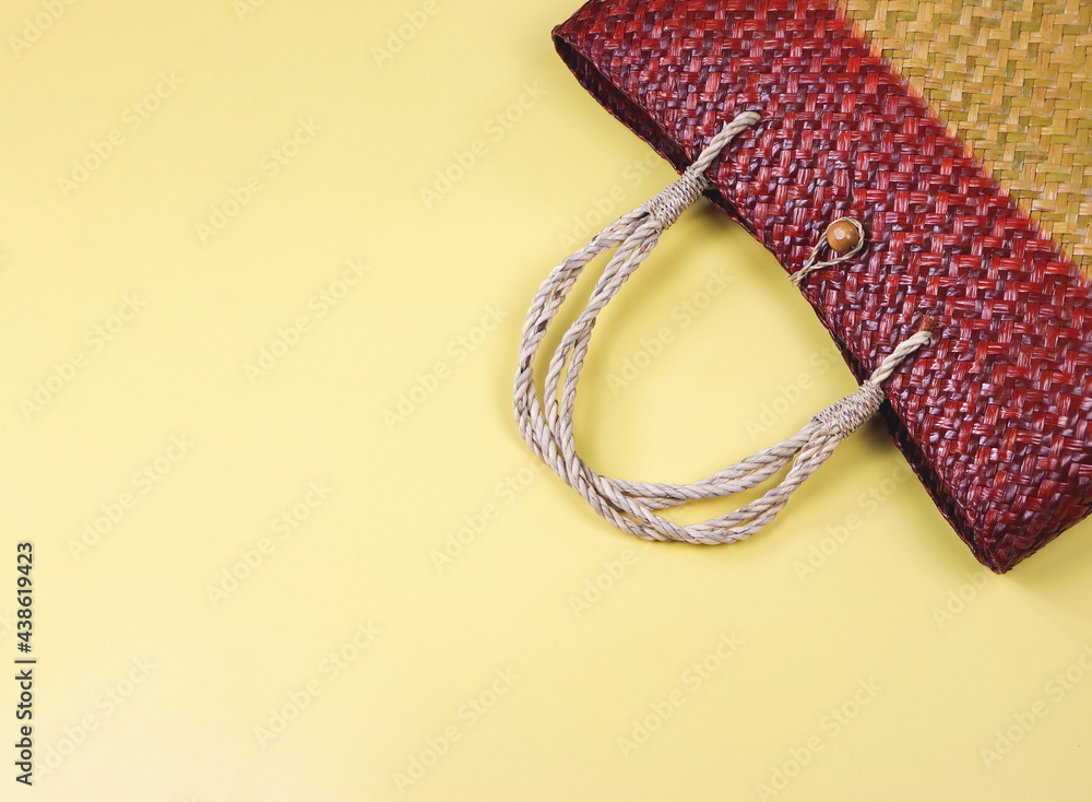 Fototapeta premium flat lay of straw bag or woven bag on yellow background.