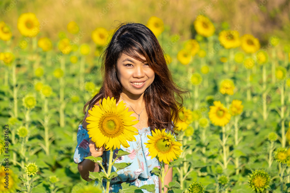 Portrait of beautiful Asian woman standing in the sunflower garden and relaxing on holiday. Portrait of beautiful Asian woman standing in the sunflower garden and relaxing on holiday.