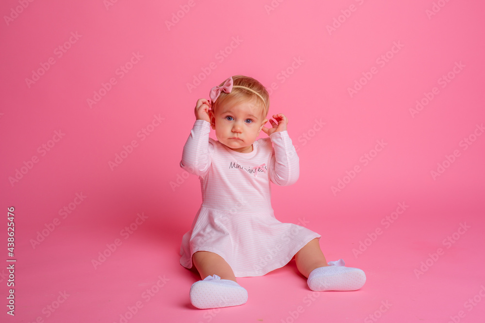 cute little baby girl in pink summer dress sitting on pink background