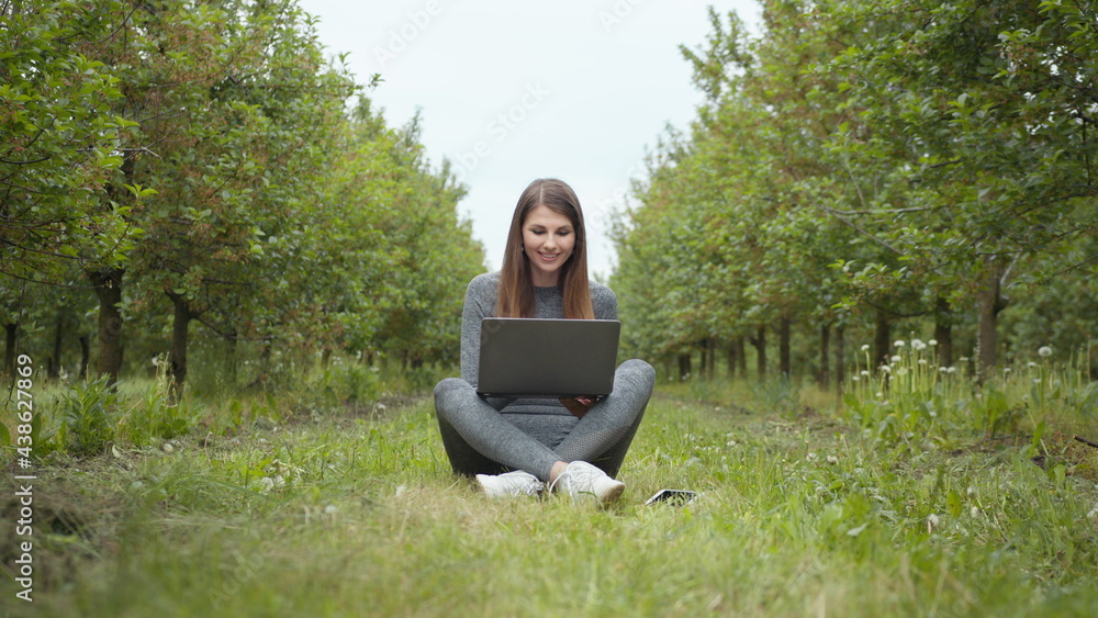 Girl sitting in park or forest, opening laptop on nature. IT specialist working at self isolation outdoors. Women engaging in business or freelance at nature or fresh air at amazing sun light. Girl sitting in park or forest, opening laptop on nature. IT specialist working at self isolation outdoors. Women engaging in business or freelance at nature or fresh air at amazing sun light.