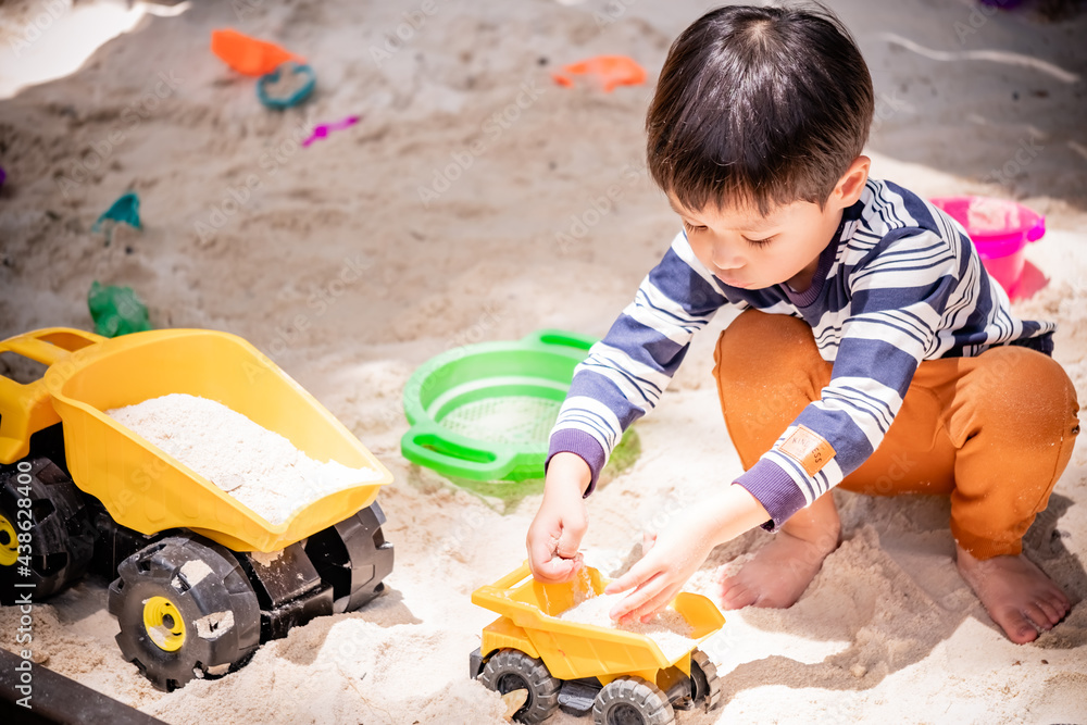 Asian child boy playing toy and sand in sandbox with natural background. Copy space. Asian child boy playing toy and sand in sandbox with natural background. Copy space.