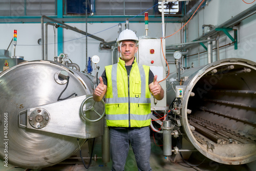 Caucasian engineer is showing trump-up in boiler machine part of beverage industry