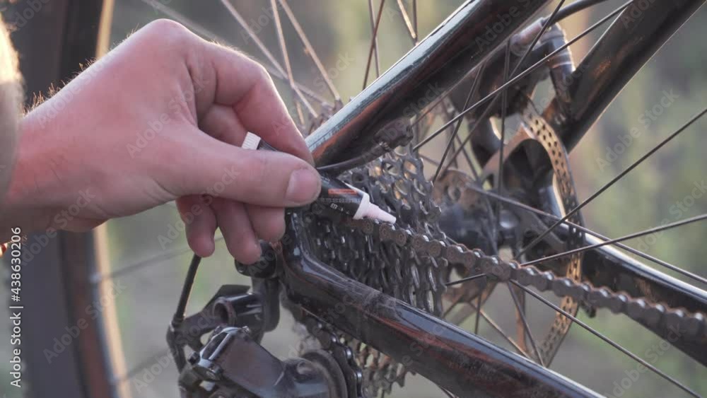 Biker lubricate bicycle chain. Man servicing his bike lubricating his