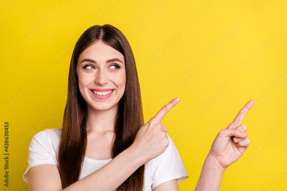 Photo of young cheerful girl happy positive smile look point fingers empty space ad choice decison promo isolated over yellow color background Photo of young cheerful girl happy positive smile look point fingers empty space ad choice decison promo isolated over yellow color background