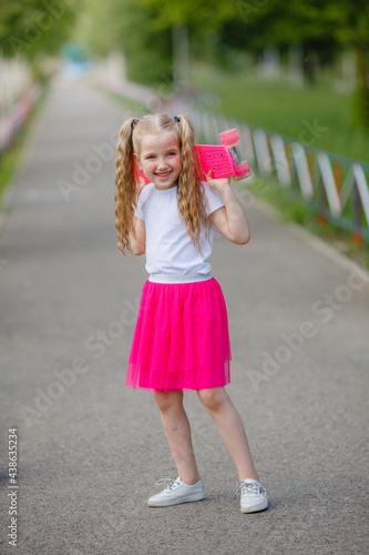 little girl skateboarding in the park in summer