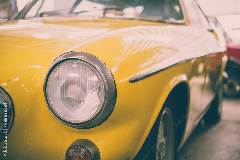 Close up round headlights of yellow vintage classic car. Transportation and retro car collection concept.