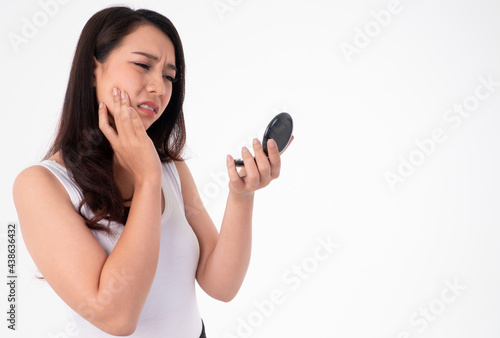 Tablou pe pânză Unhappy beautiful Asian woman squeezes acne on the face of beauty on white background