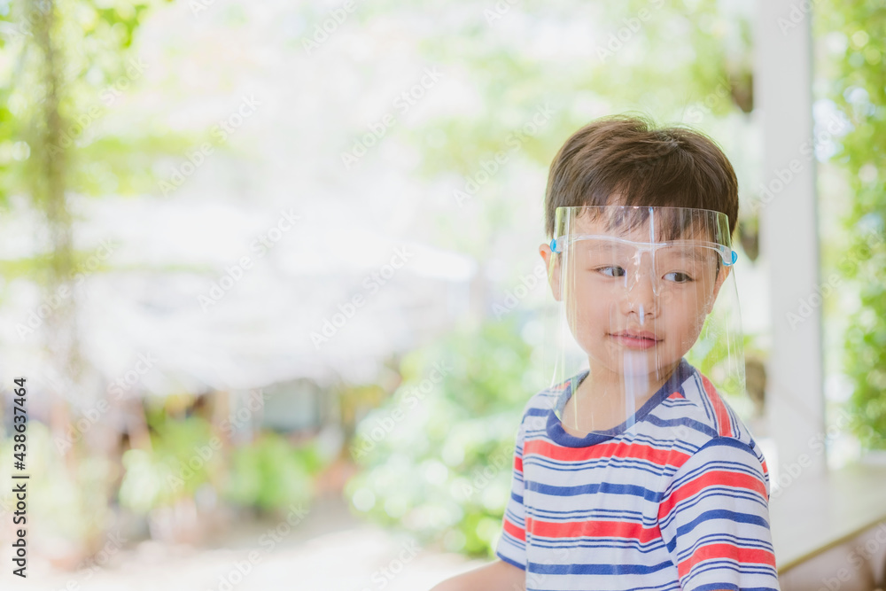 Cute little asian boy wear face mask and sheild as protection during the Covid 19 virus outbreak. Copy space. Cute little asian boy wear face mask and sheild as protection during the Covid 19 virus outbreak. Copy space.