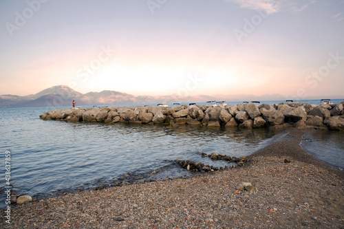 Man fishing on the rocks of the mole during a calming sunset over the harbor of Scario, Policastro gulf, Salerno, Italy.