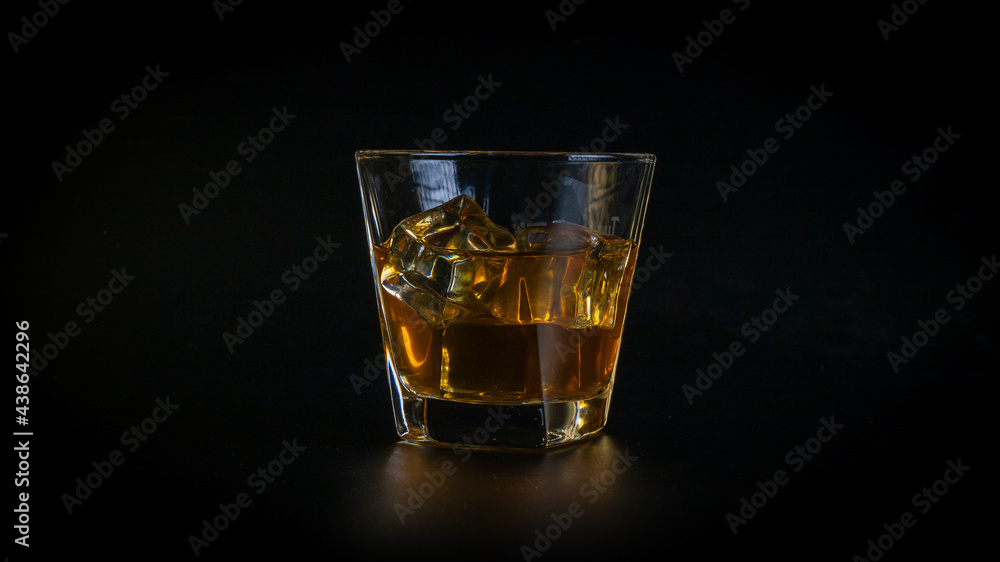 Whiskey drink or cocktail, honey brown, in a glass, full of cold, sparkling ice cubes. Whiskey drink or cocktail, honey brown, in a glass, full of cold, sparkling ice cubes.