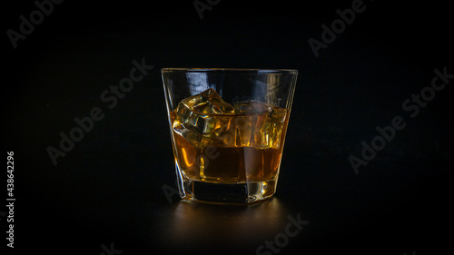 Whiskey drink or cocktail, honey brown, in a glass, full of cold, sparkling ice cubes.