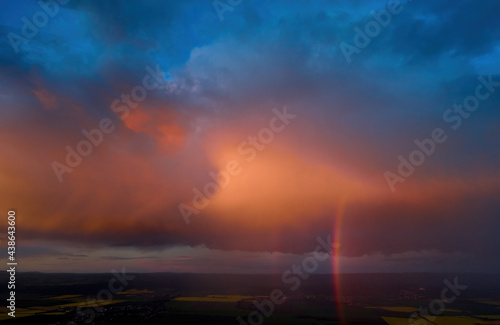 Evening  vibrant sky  pink violet blue clouds lit by setting sun. Huge rainbow over agriculture landscape. Aerial view  far horizon  ideal for sky replacement process.
