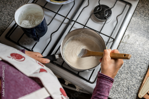 Tableau sur toile Top view of woman cooking bechamel sauce at home