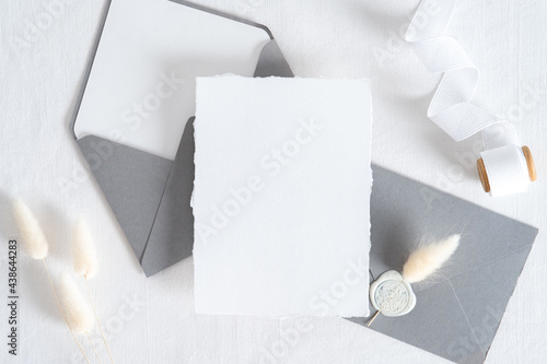 Elegant wedding stationery set. Wedding invitation card templates, grey envelopes, silk ribbon, dried flowers on white background. Flat lay, top view, copy space.