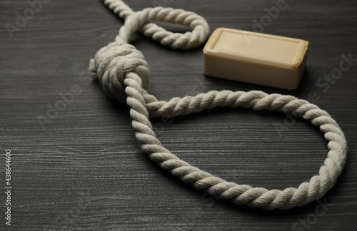 Rope noose and soap bar on dark wooden table photo