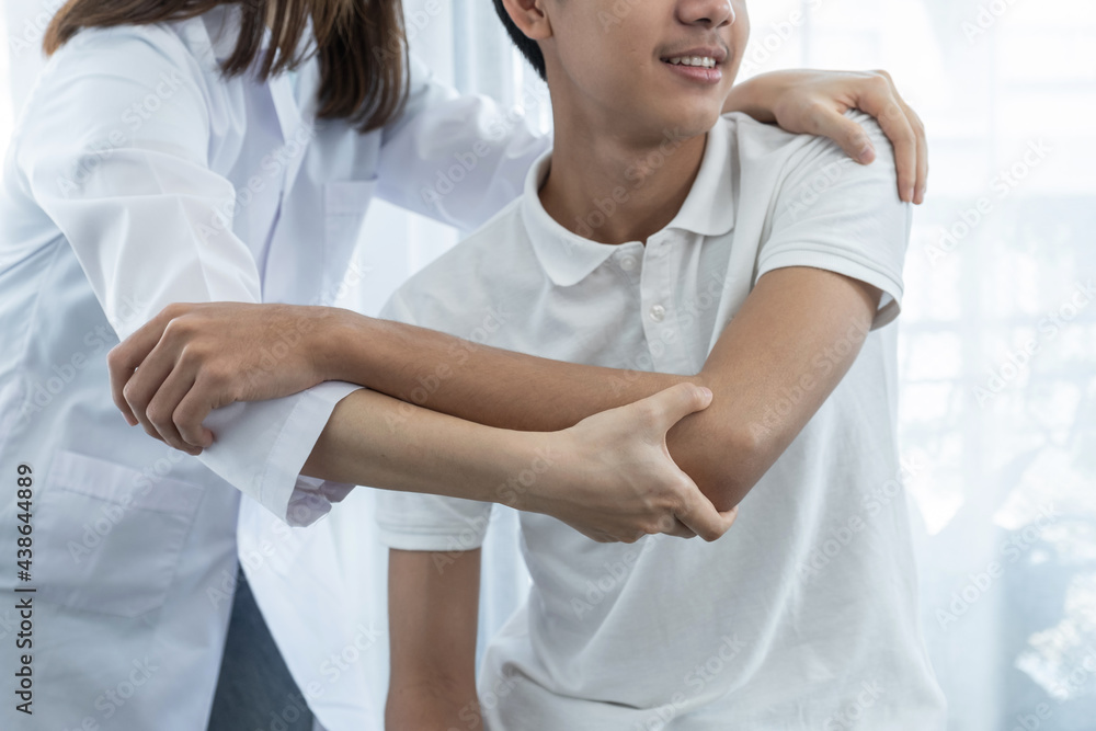 Female doctor hand doing physical therapy By extending the shoulder of a male patient Female doctor hand doing physical therapy By extending the shoulder of a male patient