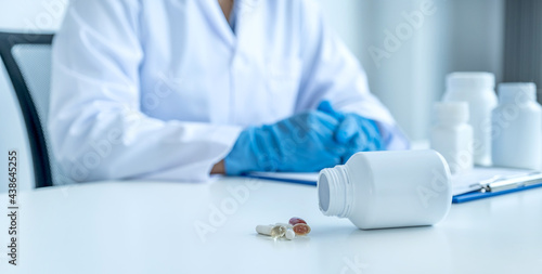Medicine pill and bottle in front of doctor or pharmacist with a prescription at the pharmacy office  healthcare and medical check-up concept