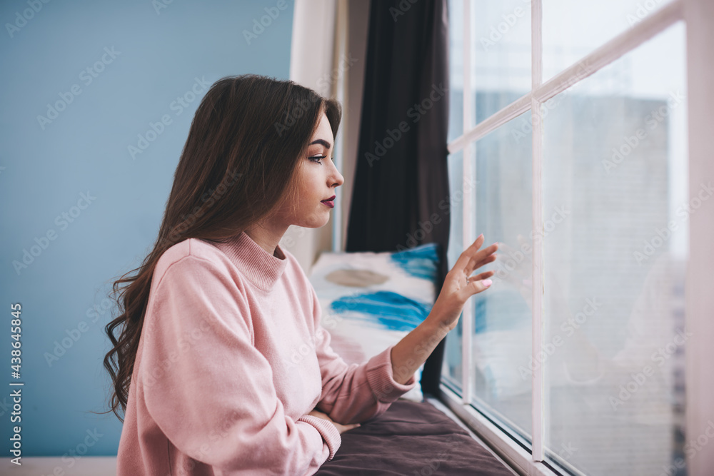 Thoughtful lonely woman touching window glass Thoughtful lonely woman touching window glass