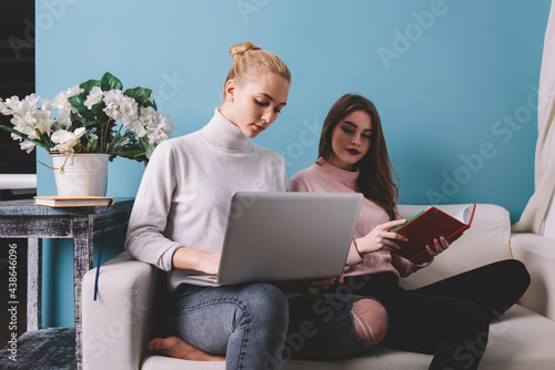 Calm female friends with laptop and book