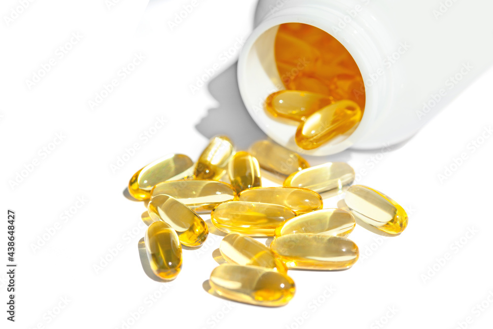 Yellow capsules of vitamin omega-3. Fish oil and omega 3 gel capsules on white background with bottle Yellow capsules of vitamin omega-3. Fish oil and omega 3 gel capsules on white background with bottle
