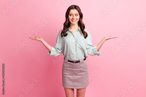 Photo of charming pretty nice young woman look empty space hold hands scales isolated on pink color background © deagreez
