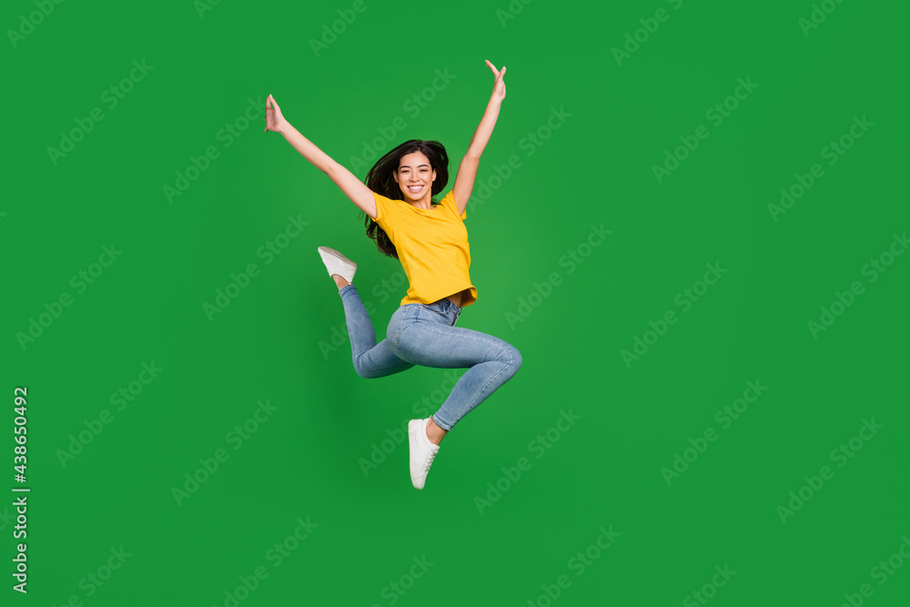 Full size photo of cheerful nice young woman jump up raise hands good mood smile isolated on green color background Full size photo of cheerful nice young woman jump up raise hands good mood smile isolated on green color background