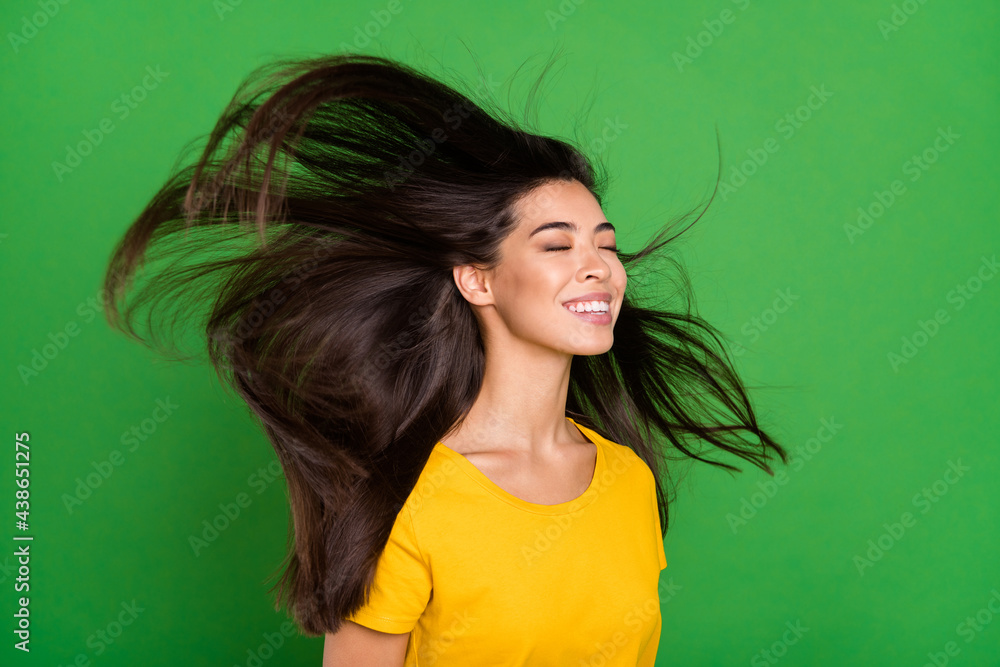 Fototapeta premium Photo portrait of dreamy girl with long brunette hair flying enjoying wind smiling isolated bright green color background copyspace